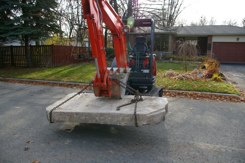 Kubota mini-excavator carrying landscape stone